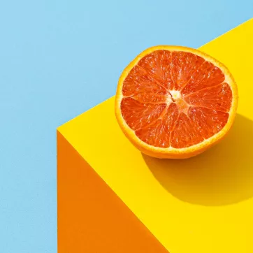 Orange sitting on an orange table with a light blue background